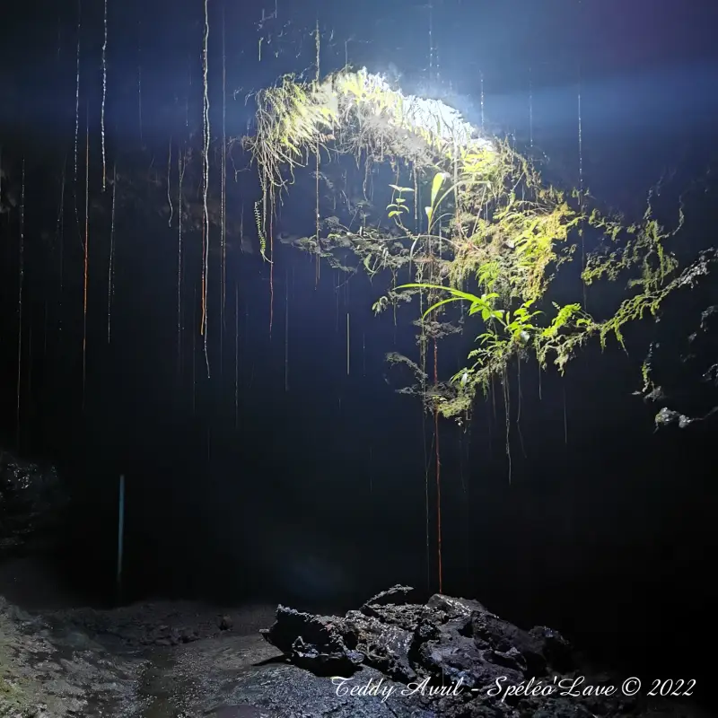 Paroi de lave figée aux reflets cuivrés, photographiée à la lumière de la frontale.