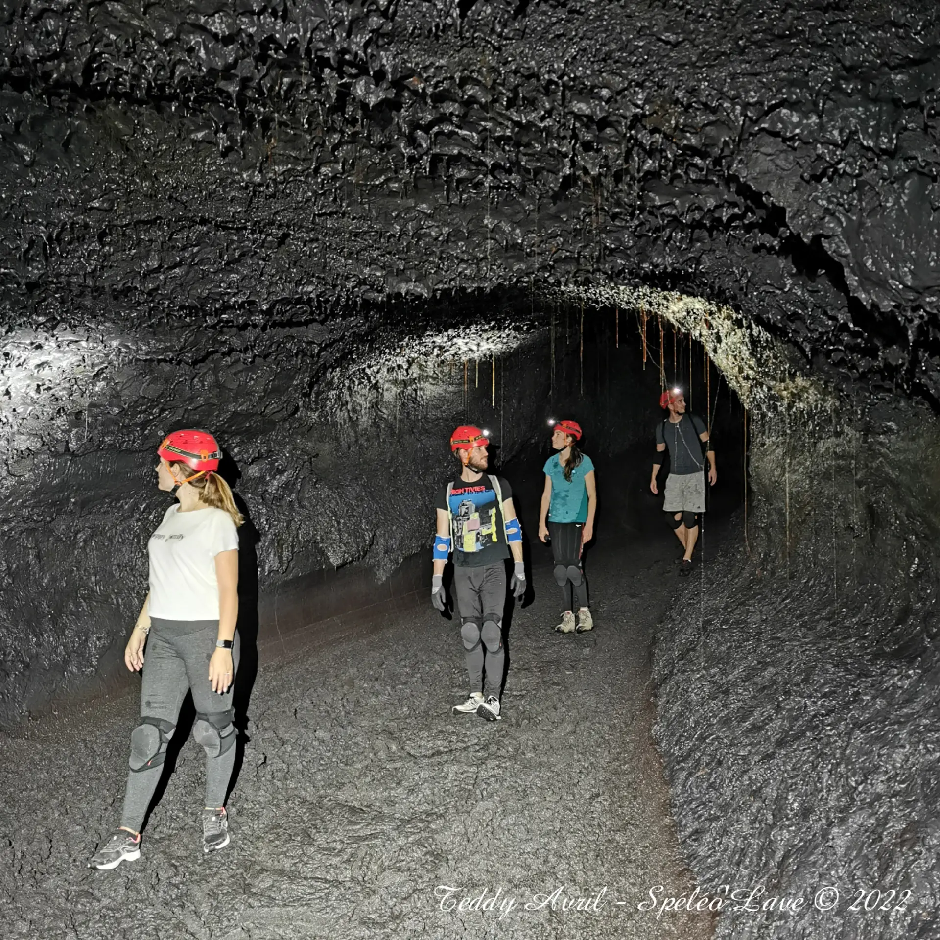 Teddy Avril en action à l'intérieur d'un tunnel de lave, frontale allumée, casque sur la tête.